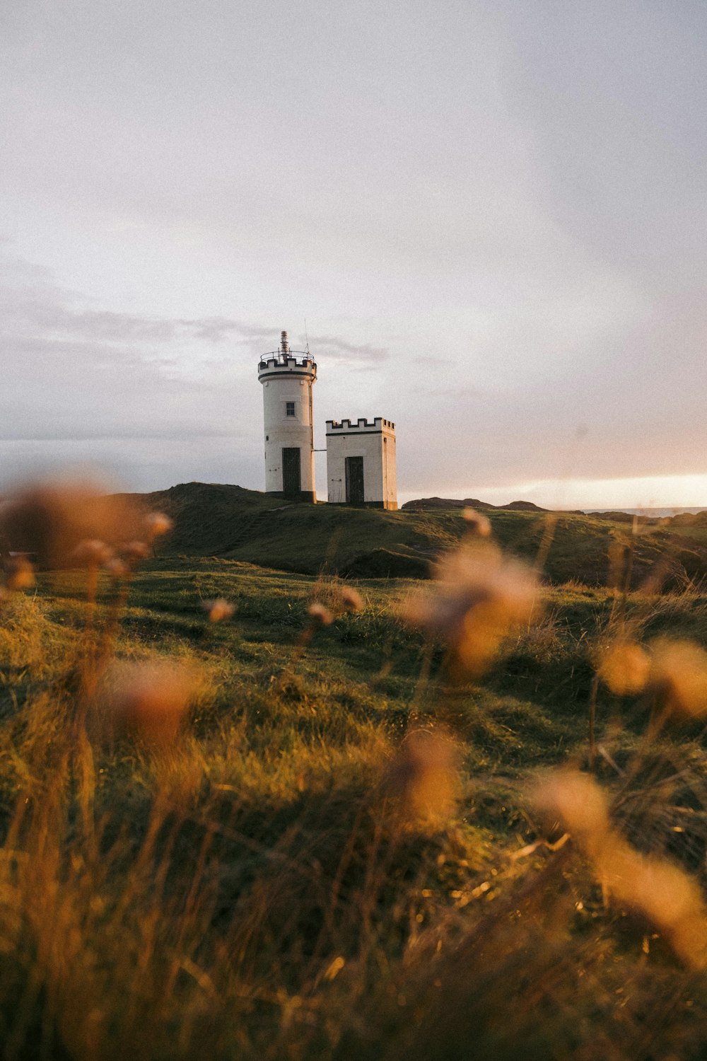 a small white lighthouse on a grassy hill