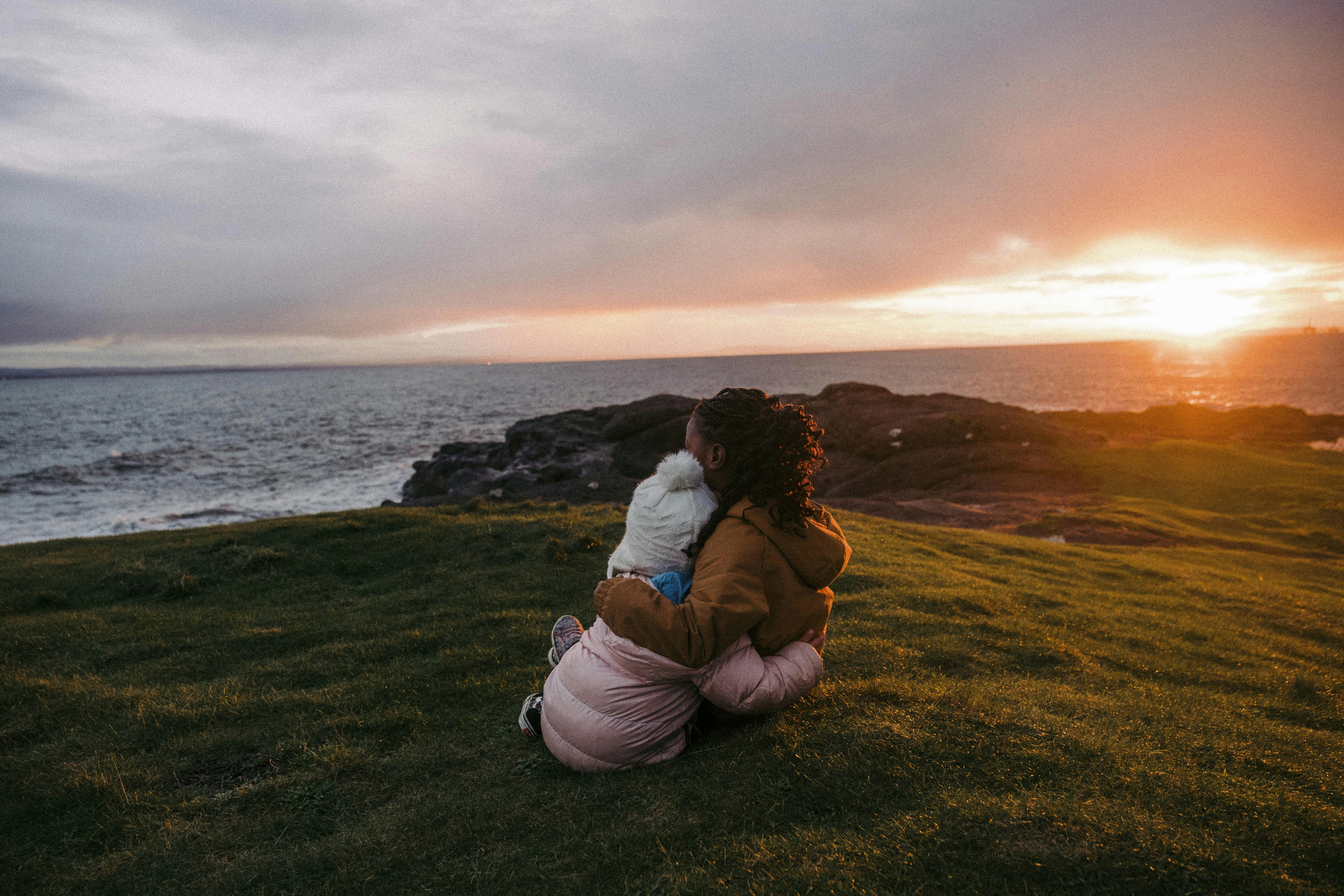 a woman sitting on the grass with a baby in her arms