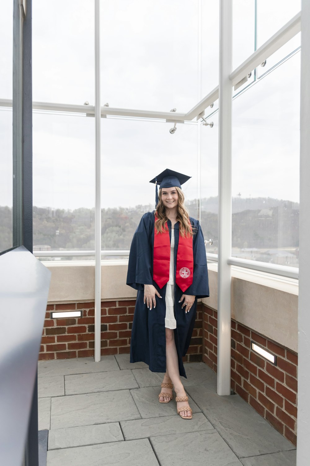 a woman in a graduation gown standing on a balcony
