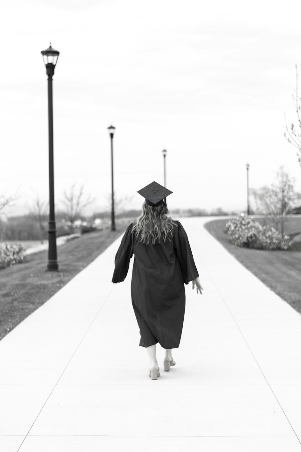 a woman in a graduation gown walking down a sidewalk