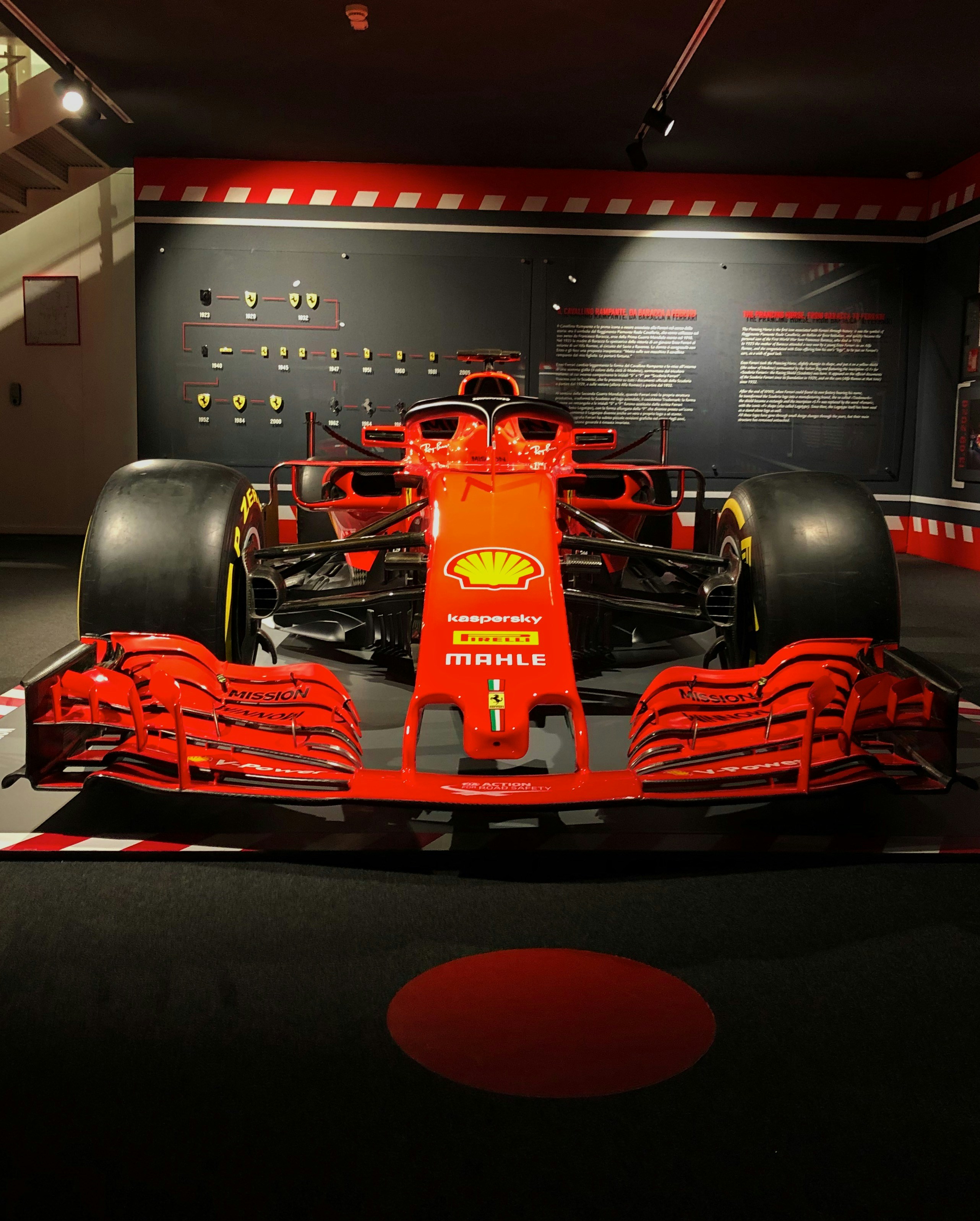 Red Ferrari F1 racing suit on dark carbon fiber background with dramatic edge lighting