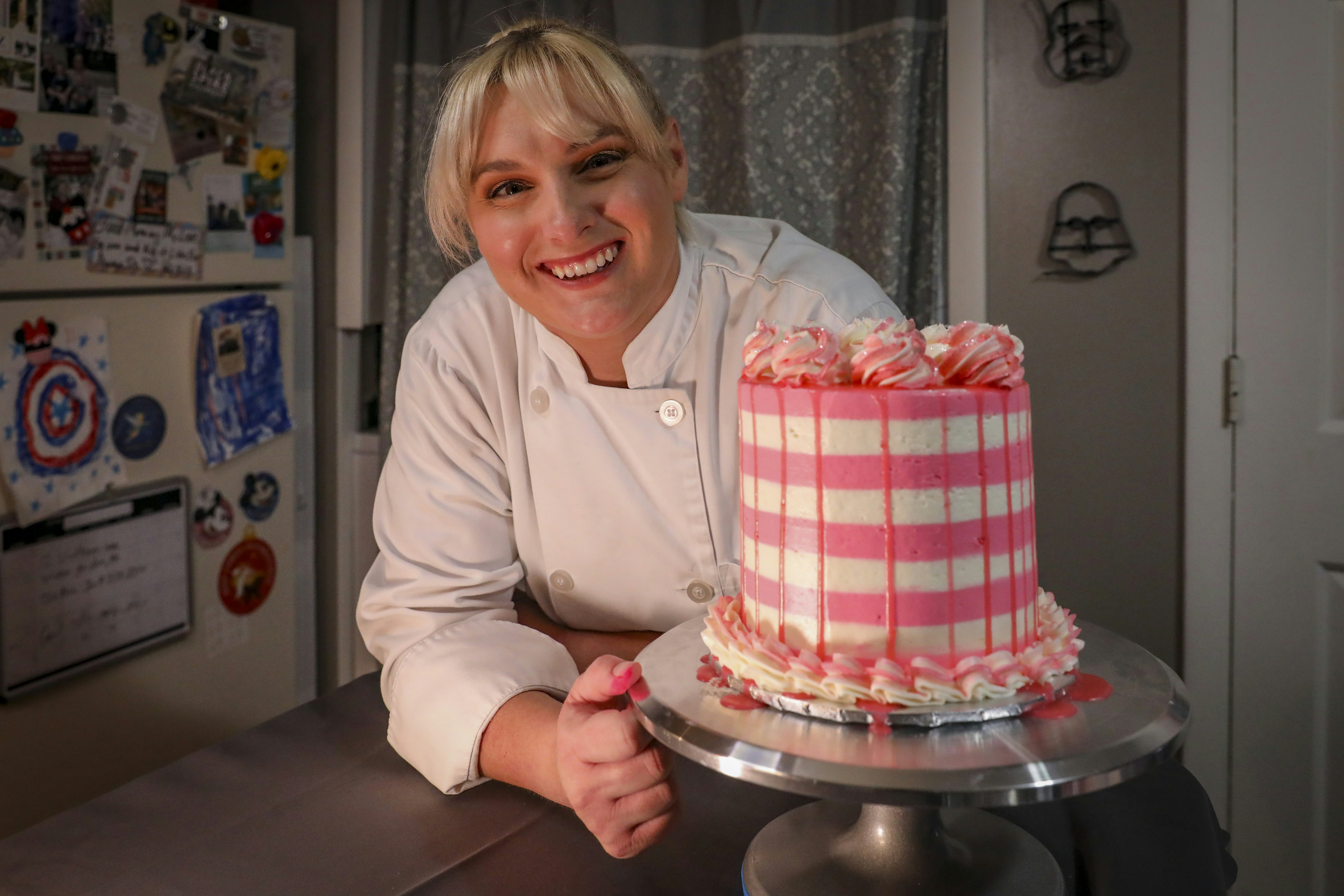 a woman in a chef's uniform is holding a cake