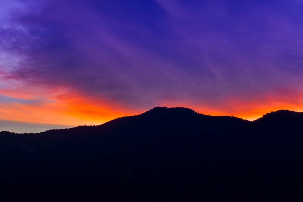 the sun is setting over a mountain range