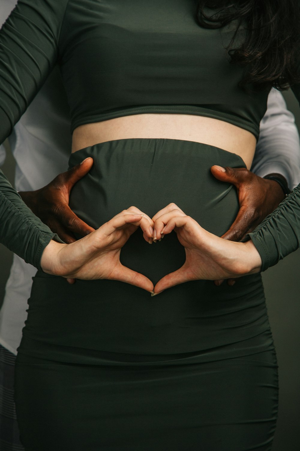 a pregnant woman making a heart shape with her hands