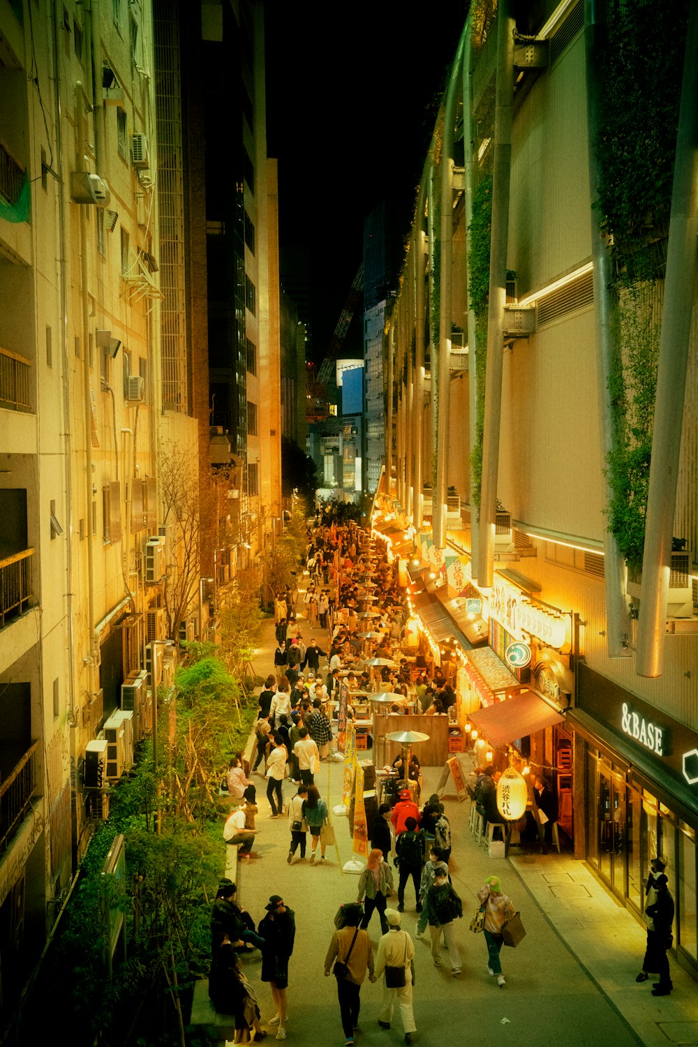 a group of people walking down a street next to tall buildings