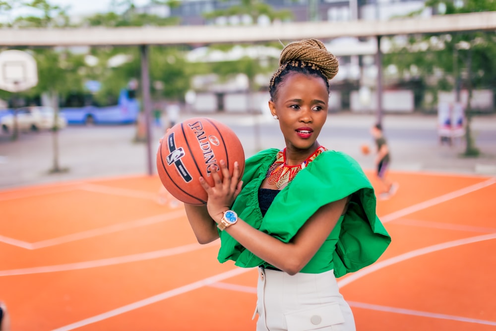 Une femme tenant un ballon de basket sur un terrain de basketball