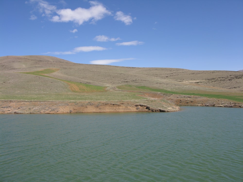 un cuerpo de agua con una colina en el fondo