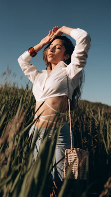 Woman wearing a flowing boho skirt standing barefoot in a sunlit field.