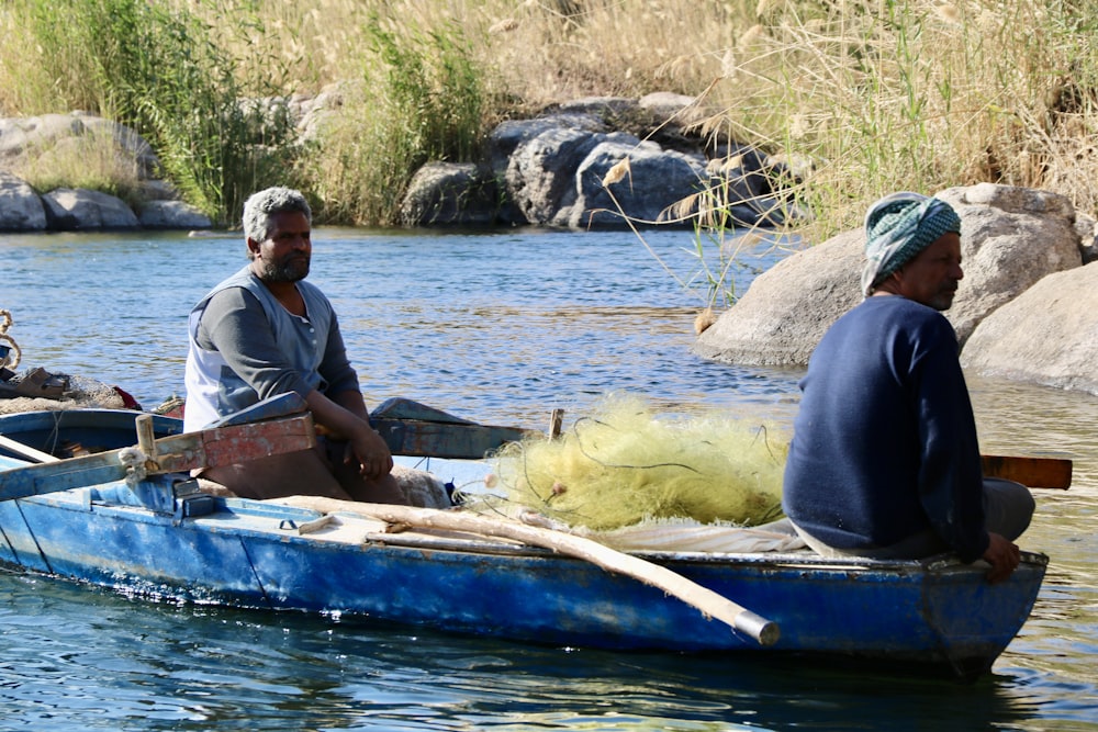 dois homens em um barco azul em um rio