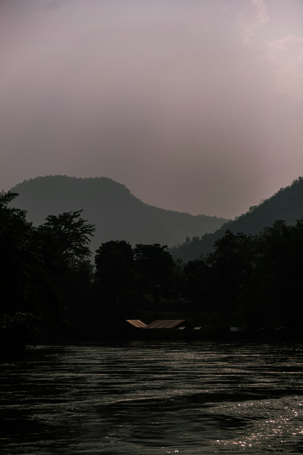 a boat floating on top of a river under a cloudy sky