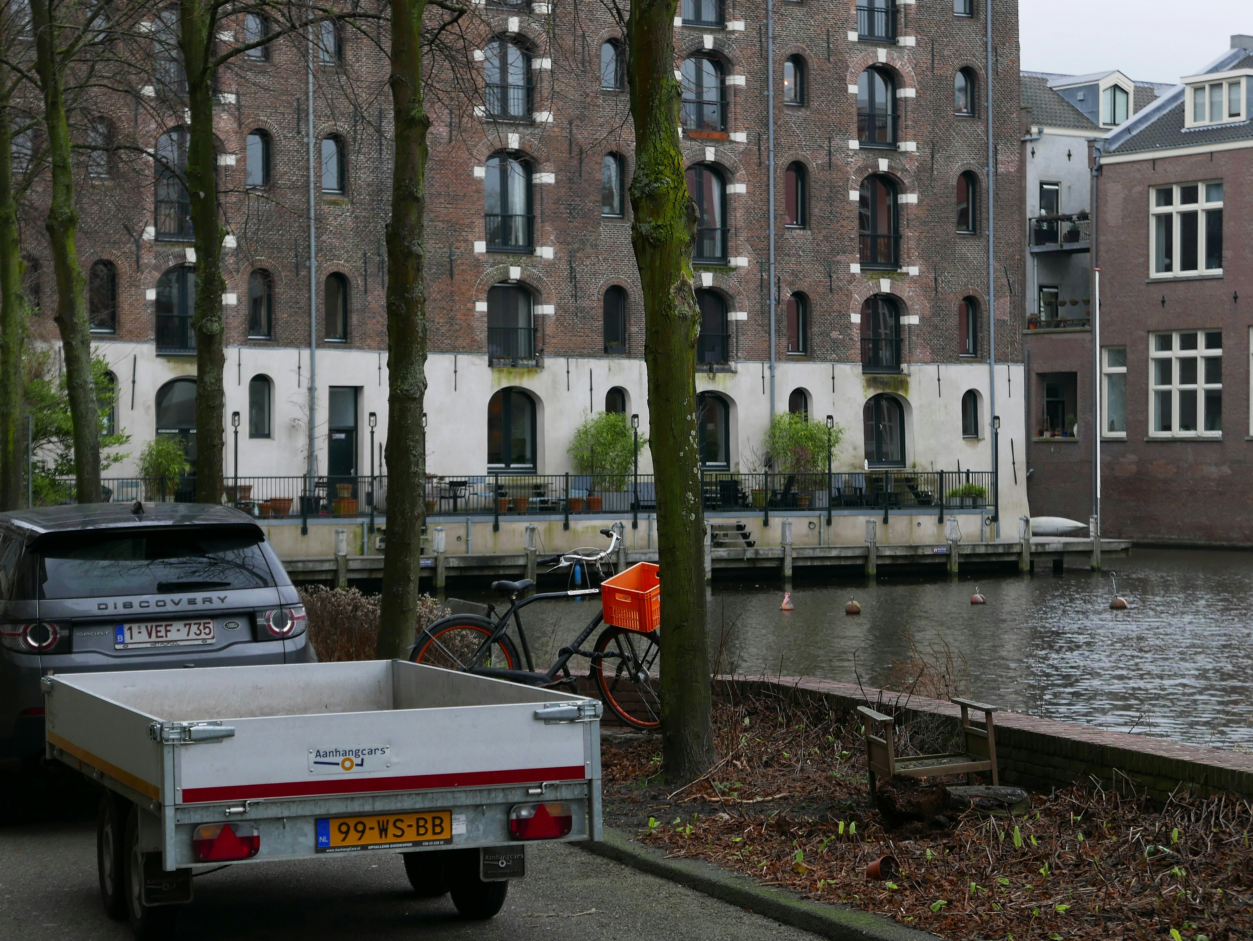 Photo of the brick back-facade of an old store house. I like the colors and the grey textures of the bricks and the water reflections. Historical architecture with functional design. Picture of Amsterdam old houses and buildings - Dutch architecture photography by Fons Heijnsbroek, Netherlands, 2022. Foto van bakstenen achtergevel van een oud pakhuis de Paerlduiker, aan het begin van de Kattenburgervaart. Oude functionele architectuur met hijs-functie. gratis downloaden. Foto, Fons Heijnsbroek - fotografie van historische gebouwen in Nederland in hoge resolutie en rechtenvrije afbeelding CCO