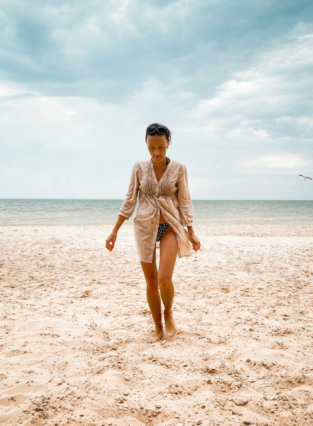 a woman walking across a sandy beach next to the ocean