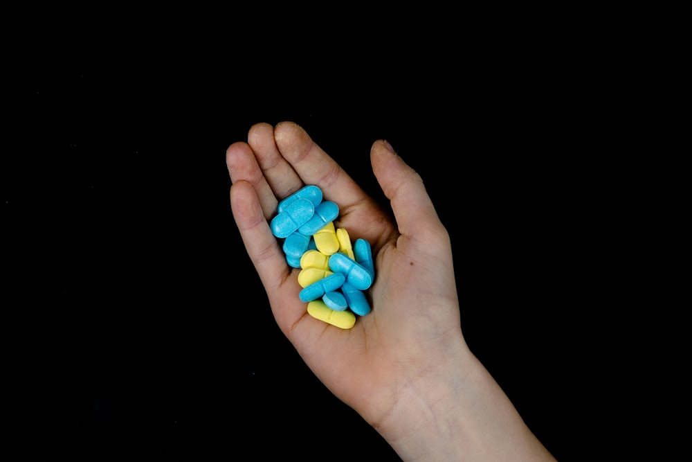 a person's hand holding a handful of pills