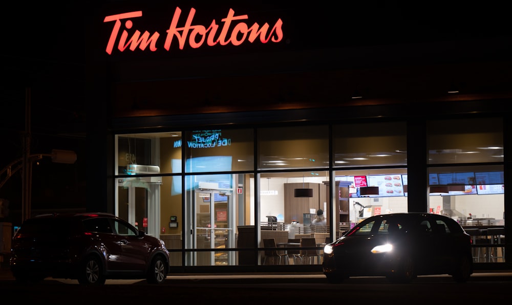 two cars parked in front of a store at night