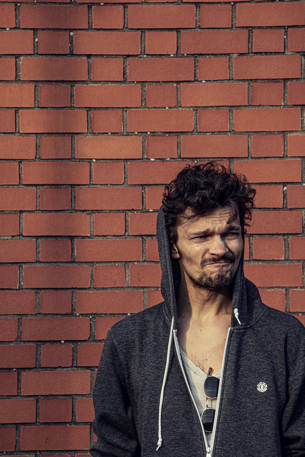 a man standing in front of a brick wall