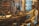 A workshop filled with a variety of vintage tools hanging on the wall. A mannequin dressed in vintage attire is seated, appearing as if working with the machinery on the wooden table. The workshop has a rustic feel with wooden shelves and brick walls.