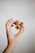 A hand gently holds a small, intricate wooden puzzle against a plain, light background. The puzzle consists of interlocking wooden pieces, suggesting complexity and craftsmanship.