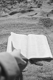 An open book with diverse hands reaching out to it.