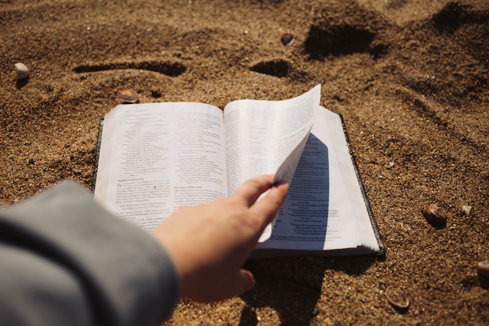 a person is reading a book in the sand