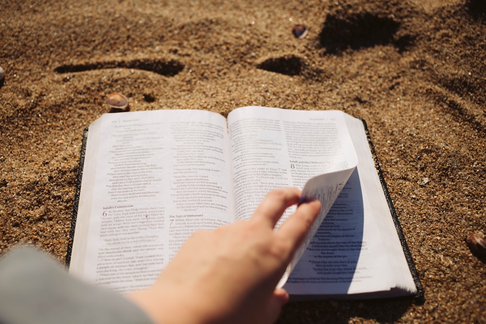 a person is reading a book in the sand