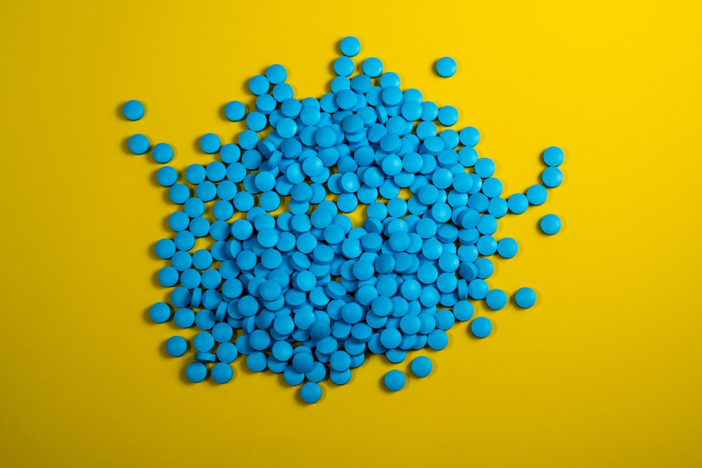 Ein Haufen blauer Pillen auf gelbem Hintergrund