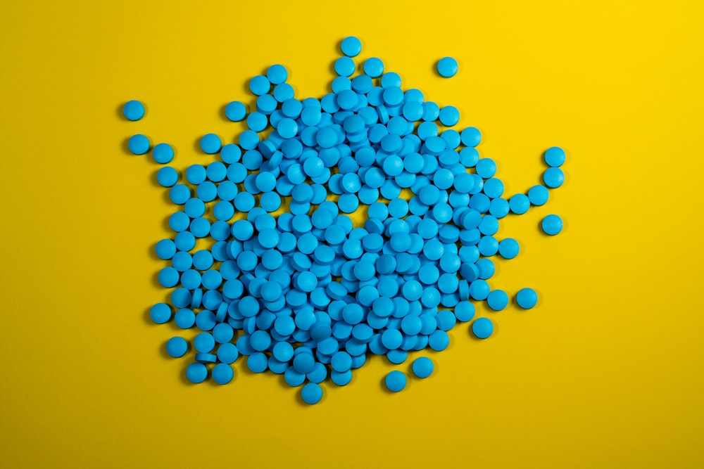 Un montón de pastillas azules sobre un fondo amarillo