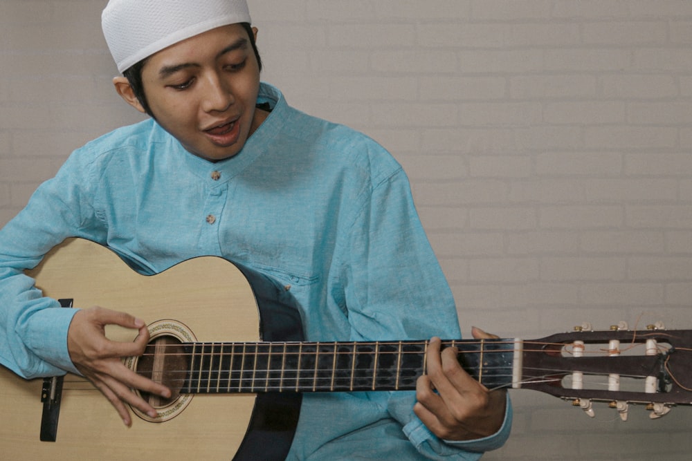 a man in a blue shirt playing a guitar