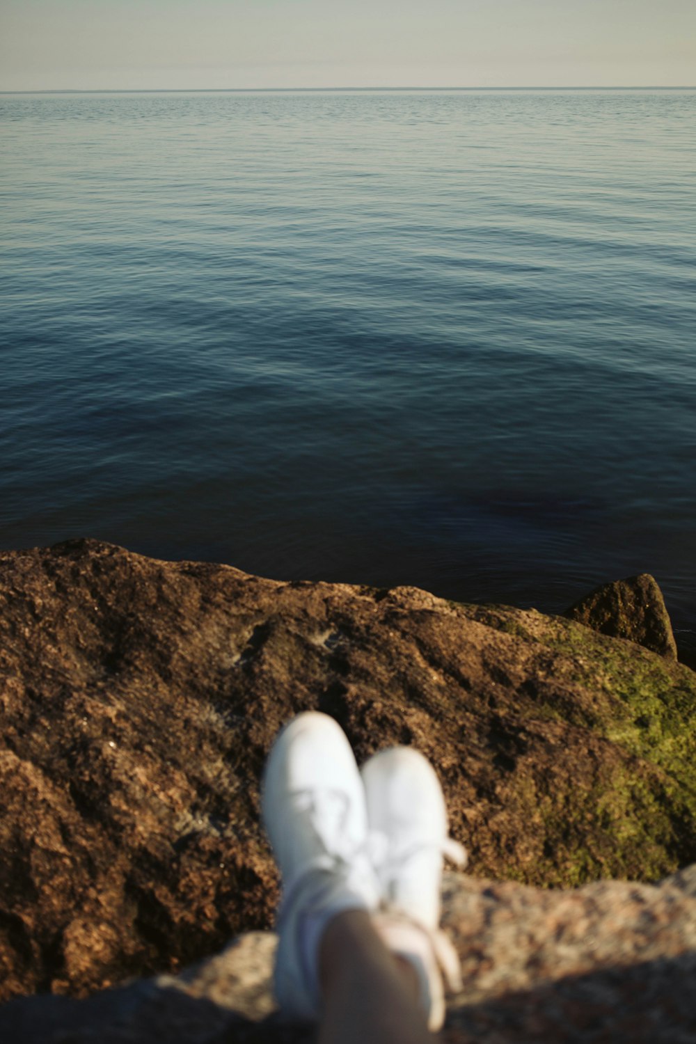 a person is sitting on a rock near the water