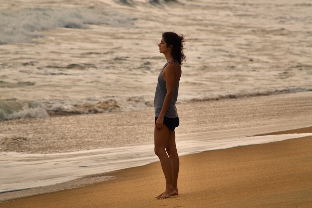 a woman standing on a beach next to the ocean