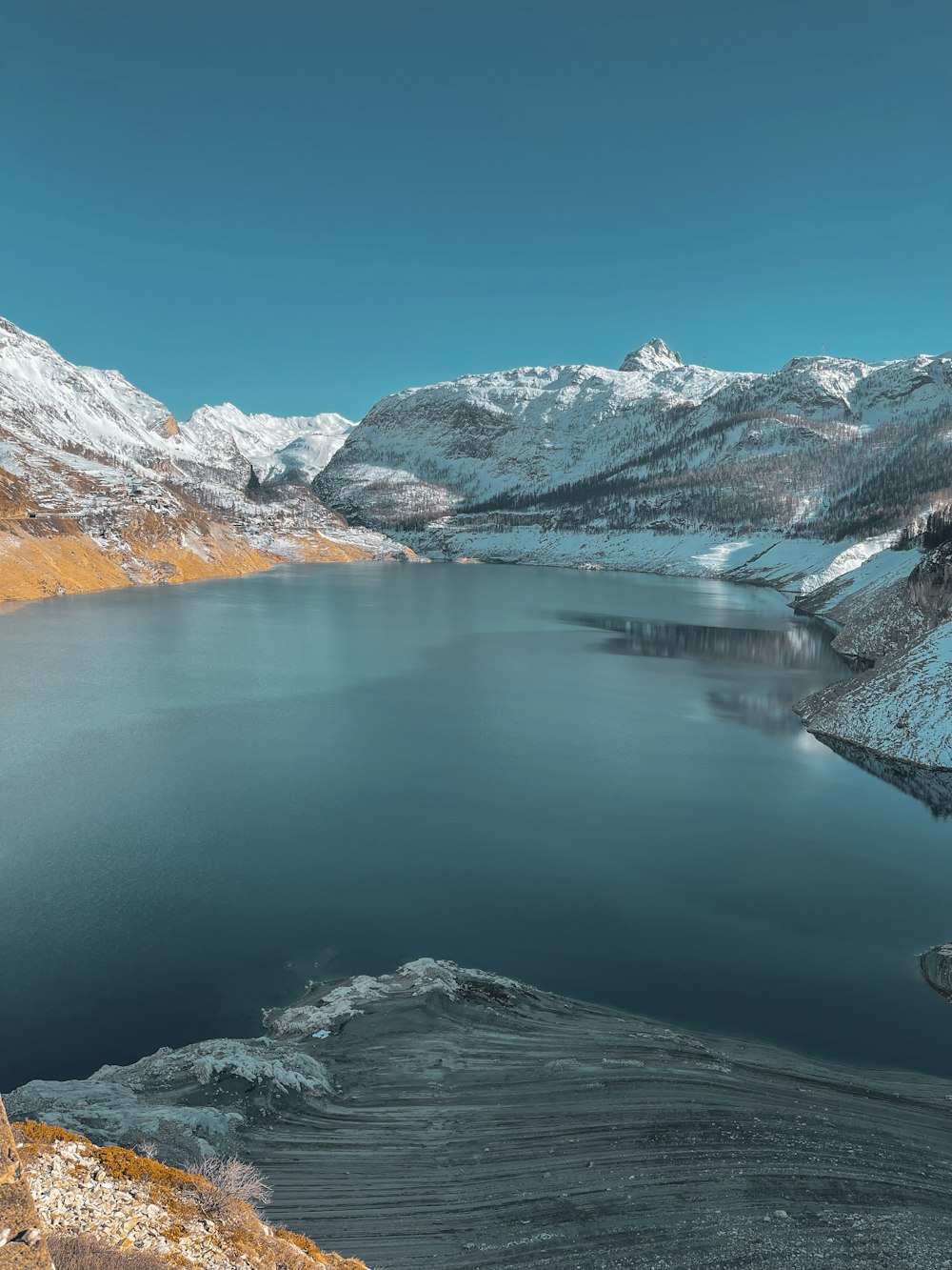 a large body of water surrounded by snow covered mountains