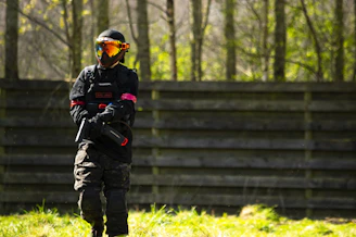 A dynamic photo of players in tactical gear engaging in a paintball match amidst an industrial, urban battlefield setting.