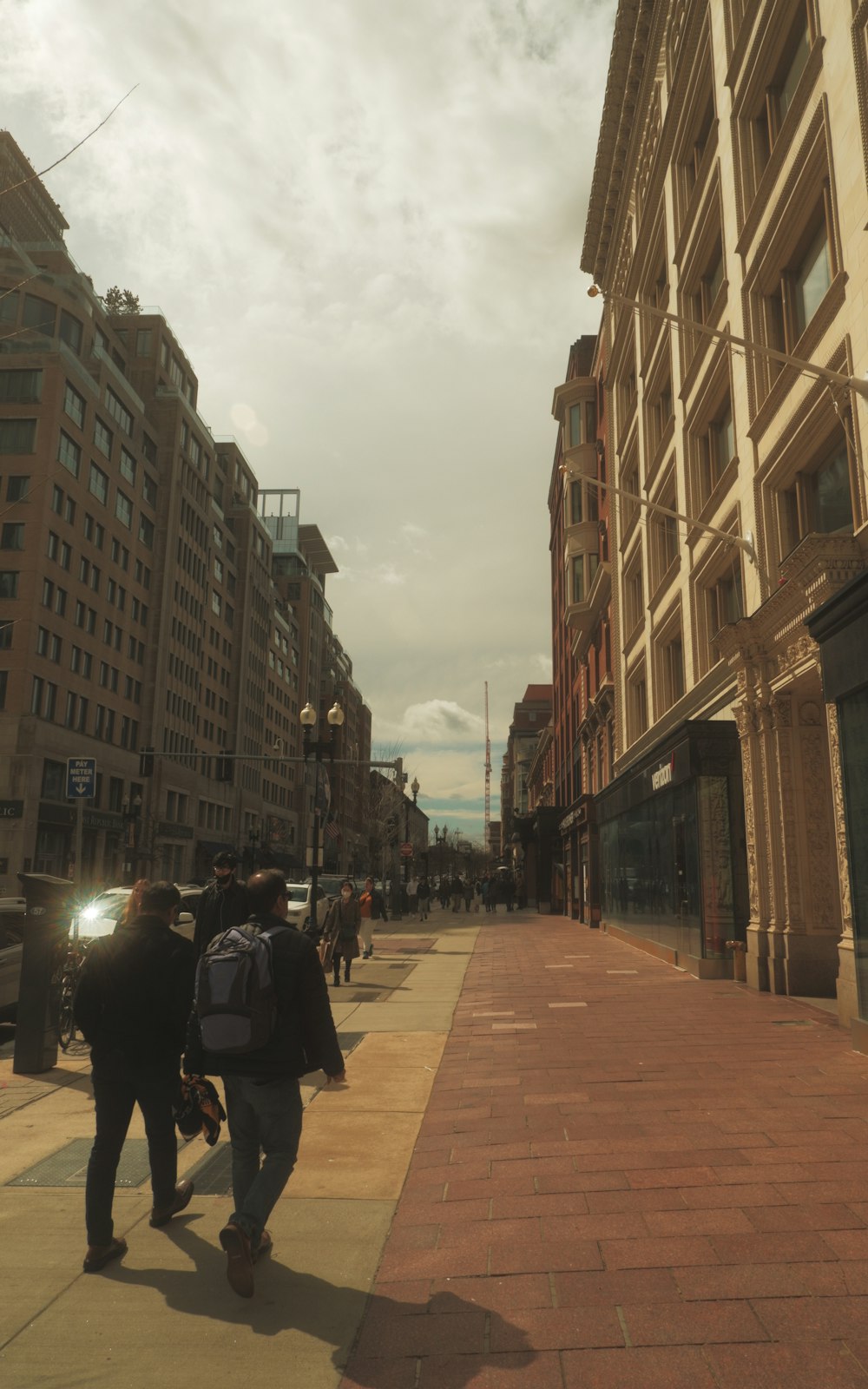 a group of people walking down a street next to tall buildings