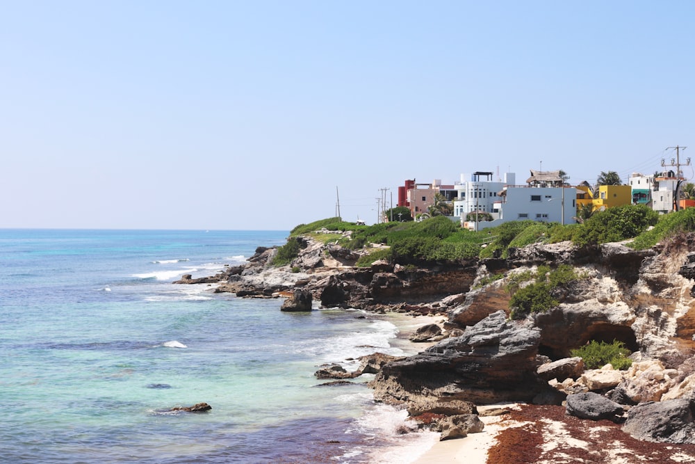 a view of a beach with houses on the cliff