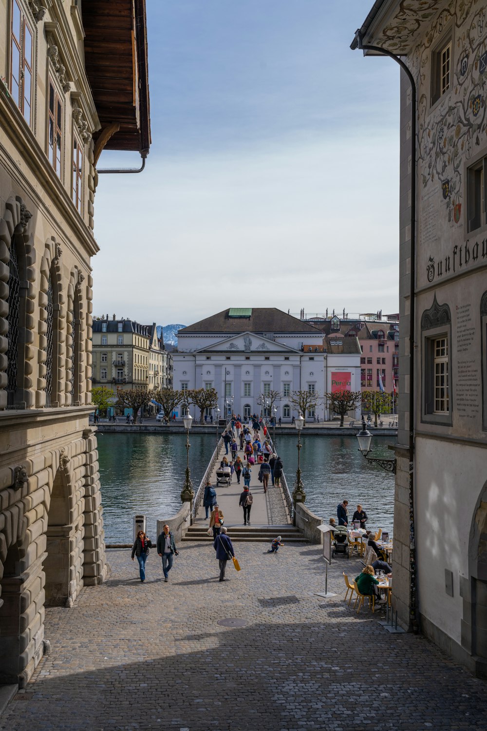 a group of people walking down a street next to a body of water