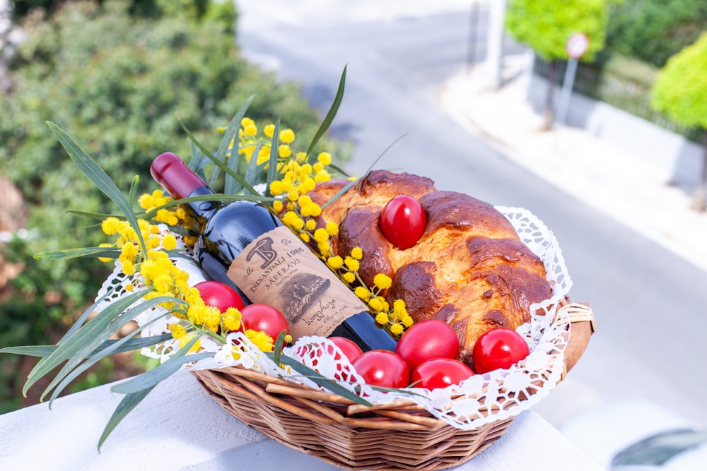 a basket filled with bread, tomatoes and a bottle of wine