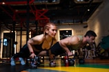 a man and a woman doing push ups with dumbbells