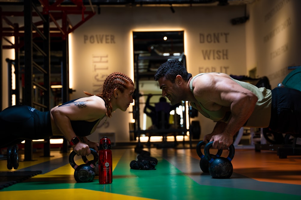 a man and a woman doing push ups with kettles