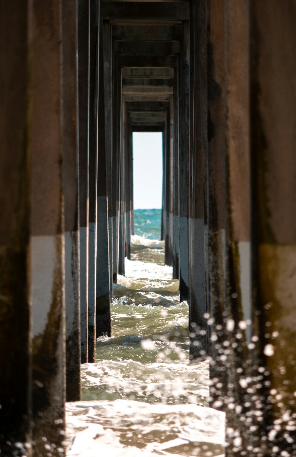 a view of the ocean from underneath a pier