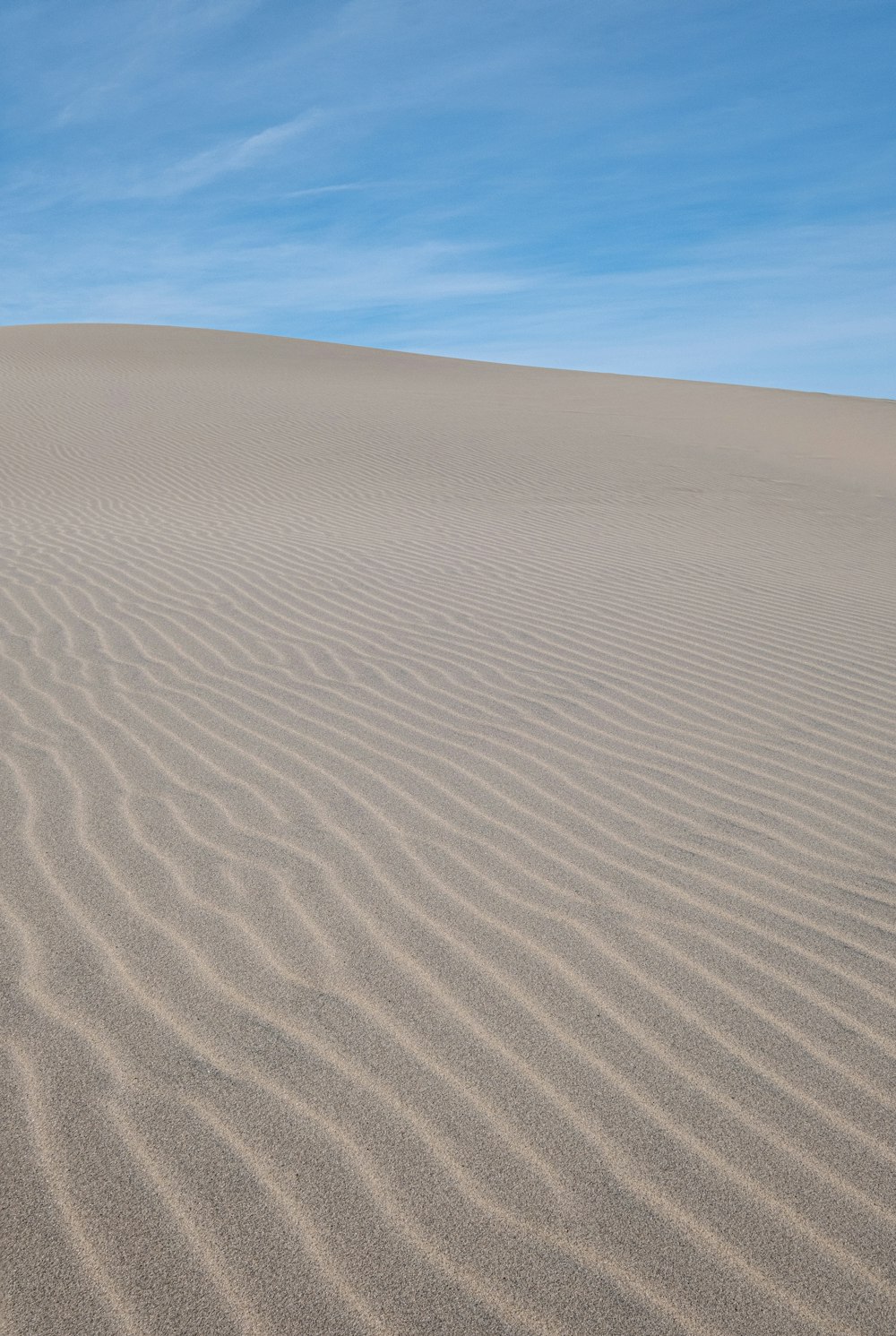 une grande dune de sable avec un ciel bleu en arrière-plan