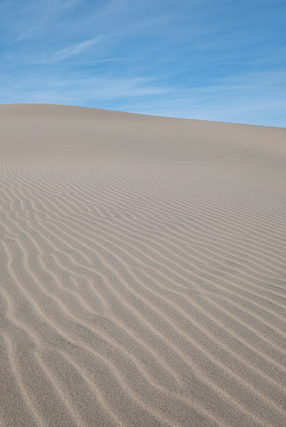 a large sand dune with a blue sky in the background