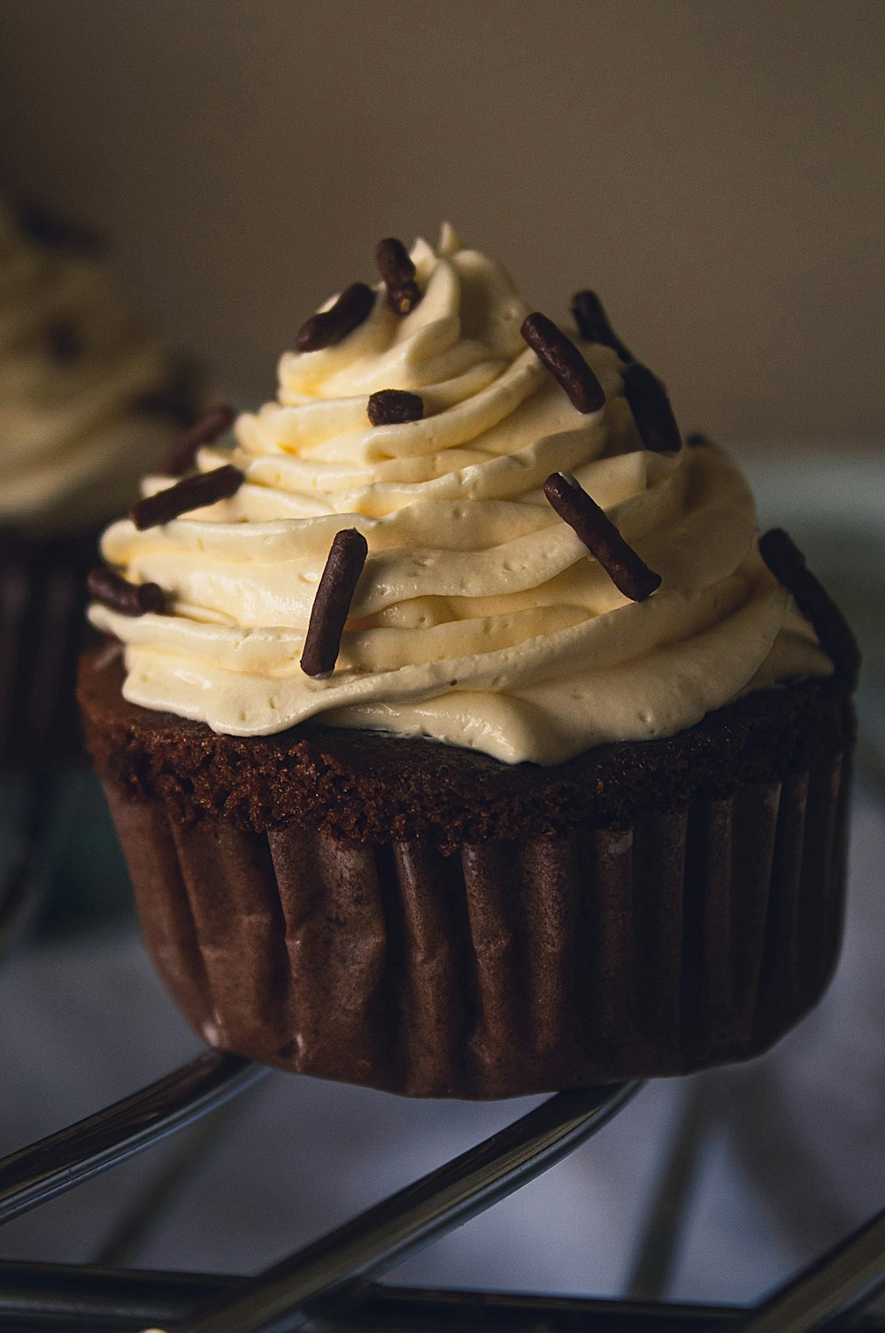 a chocolate cupcake with white frosting and chocolate sprinkles