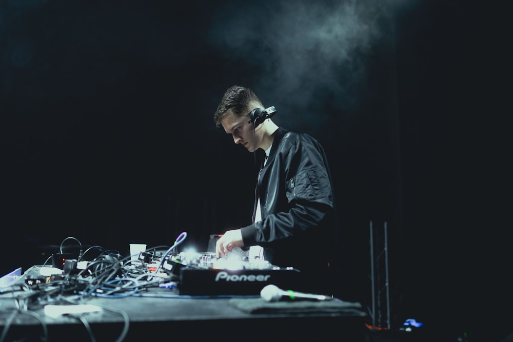 a man in a black jacket is djing at a table