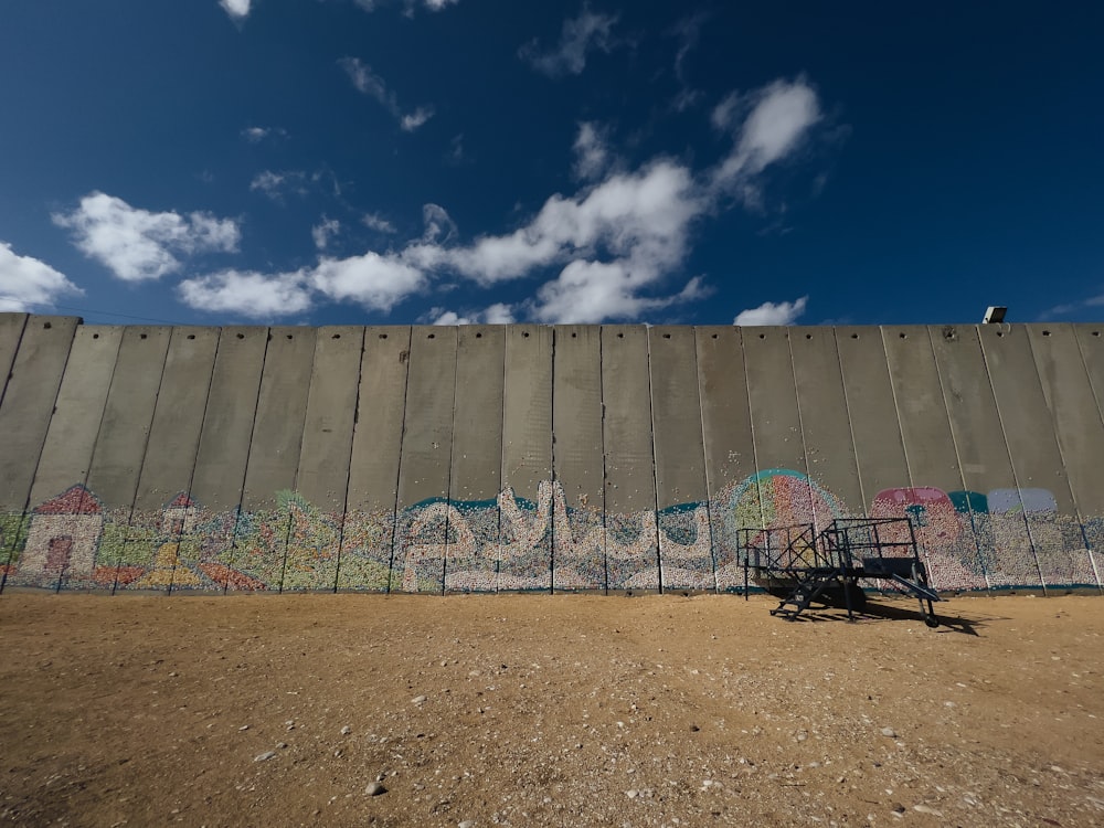 un mur avec des graffitis dessus et un banc devant lui