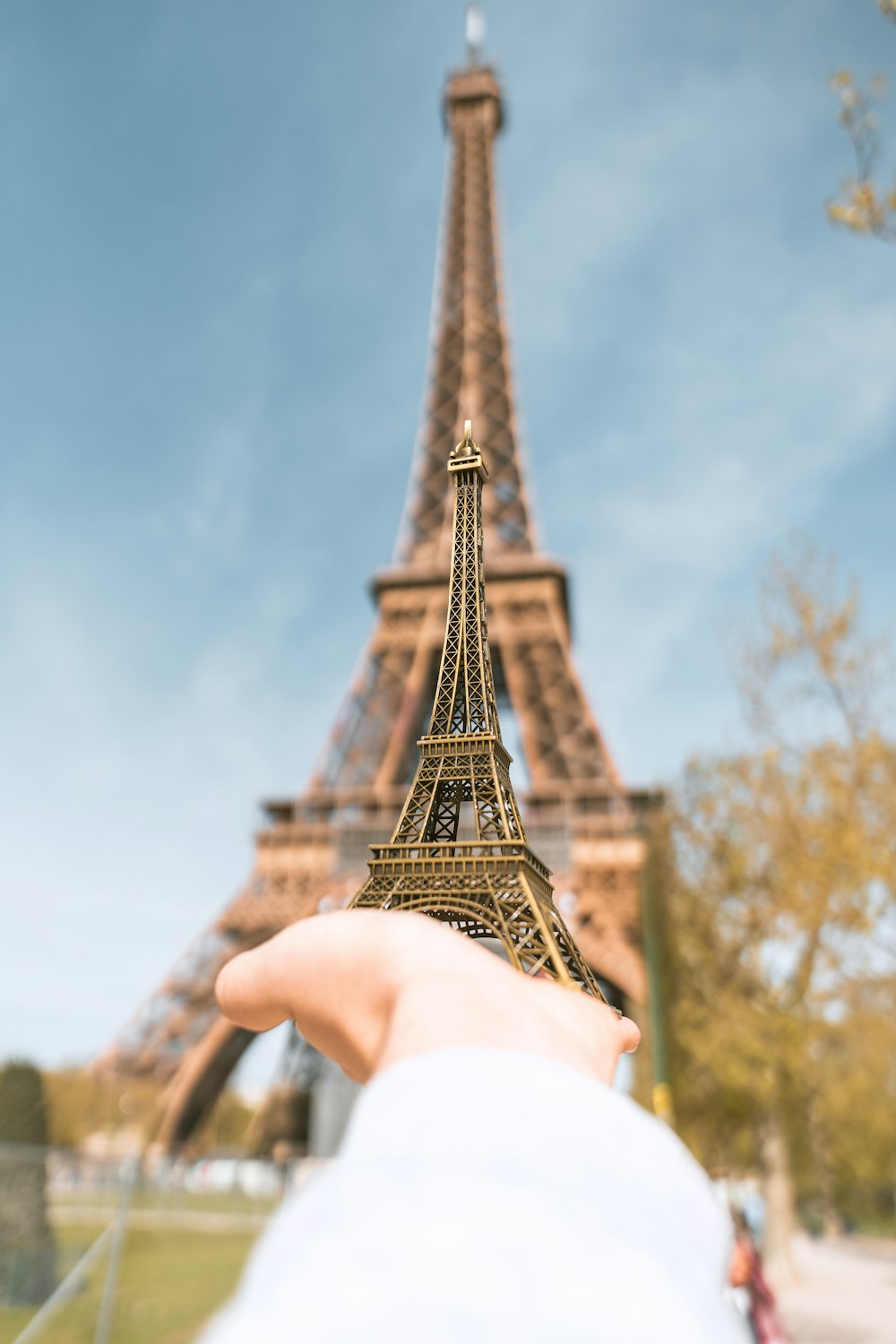 a hand holding a miniature model of the eiffel tower