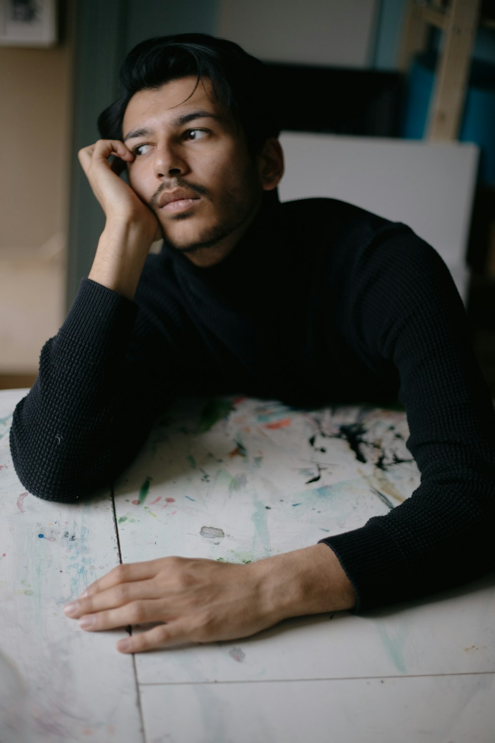 a man sitting at a table with his hand on his head