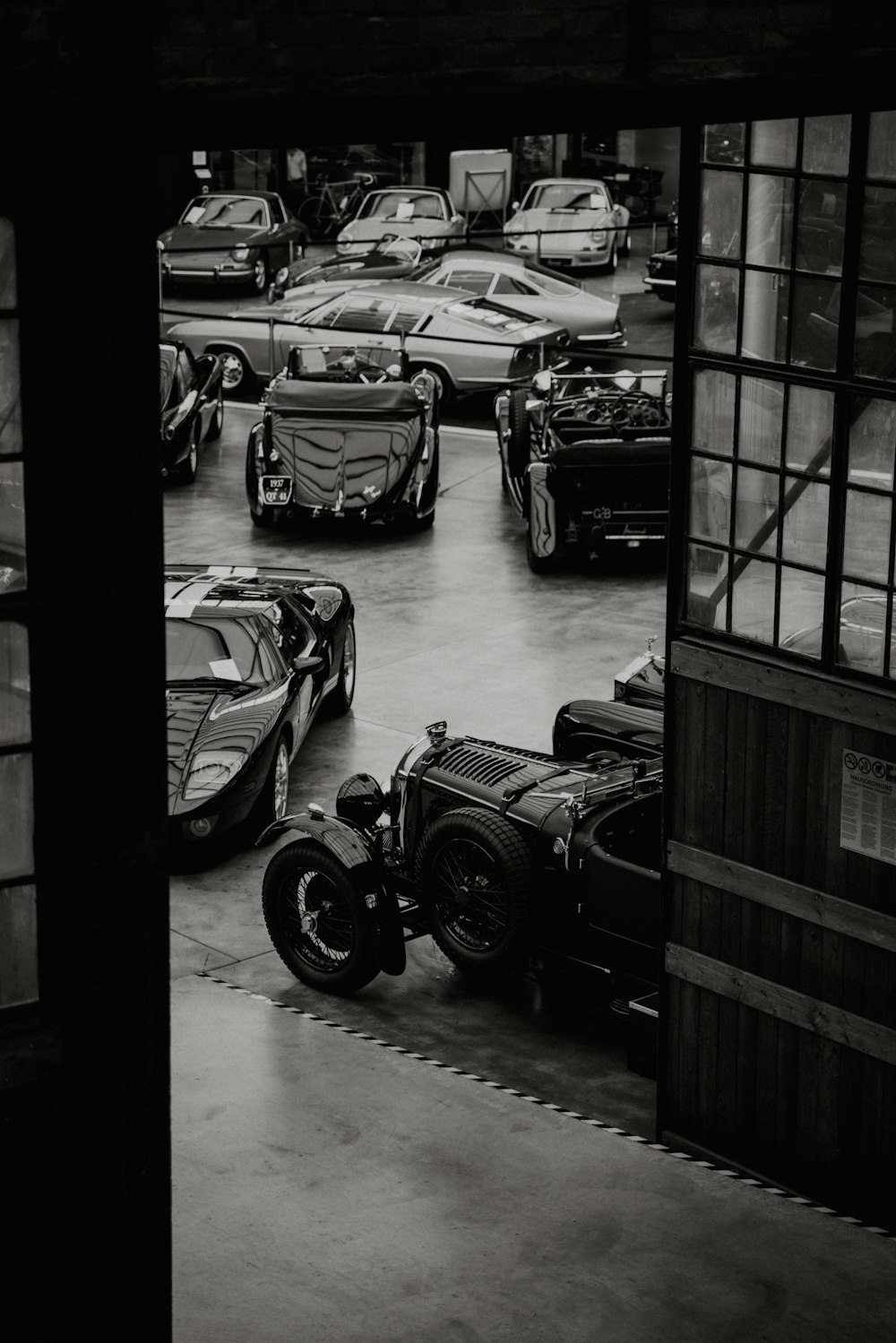 a black and white photo of a garage full of cars
