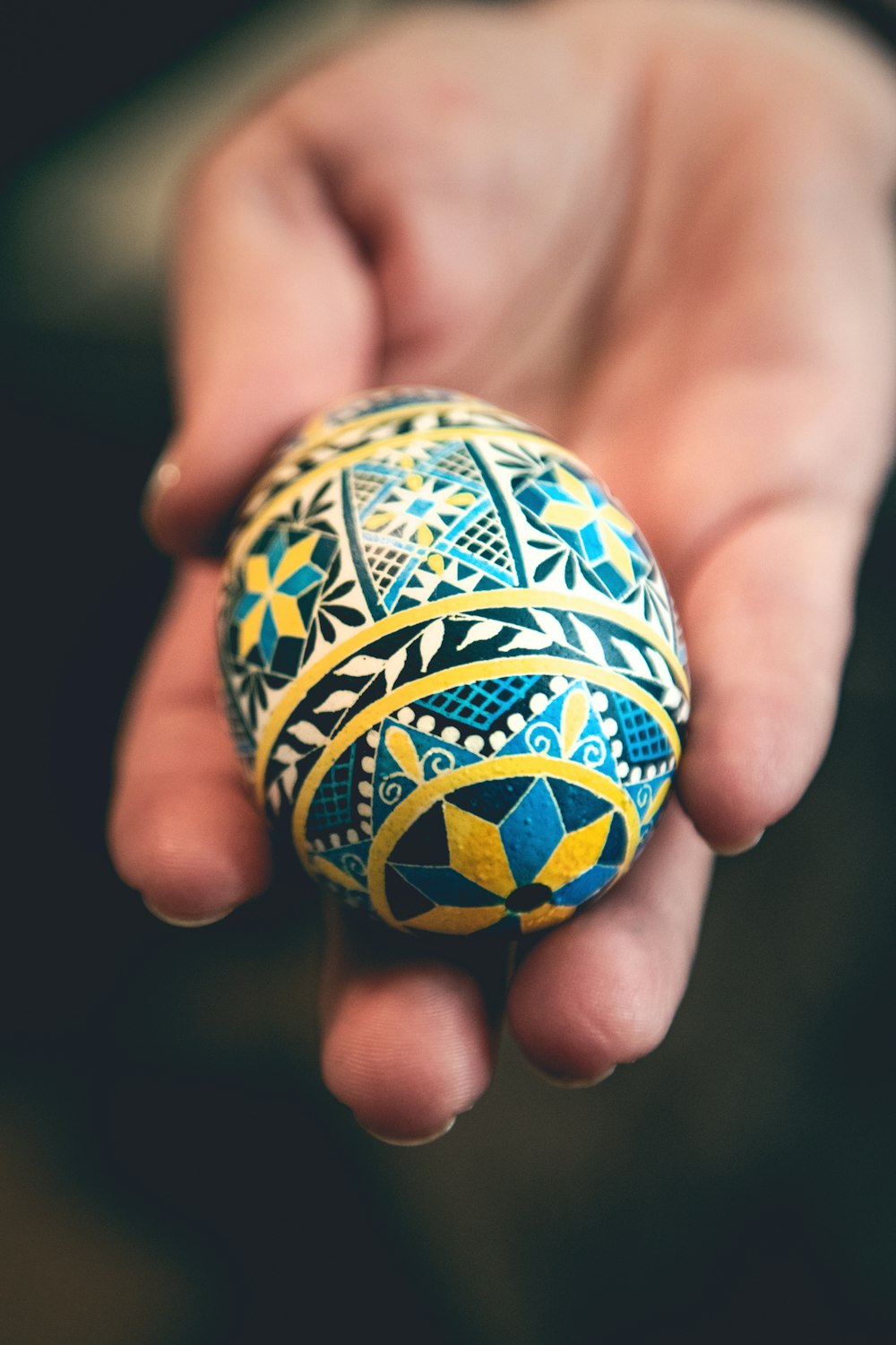 a person holding a painted egg in their hand
