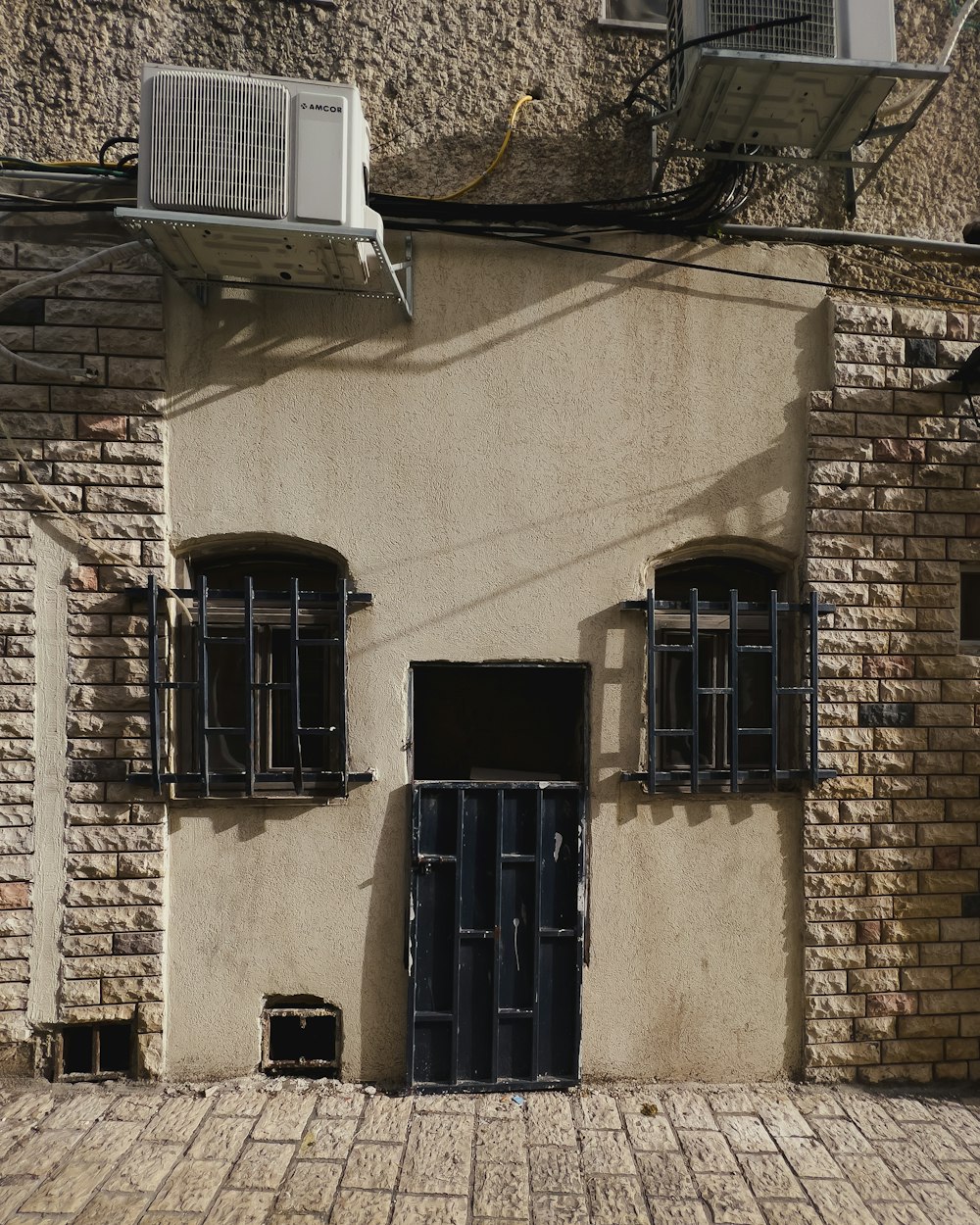 a brick building with two windows and a air conditioner