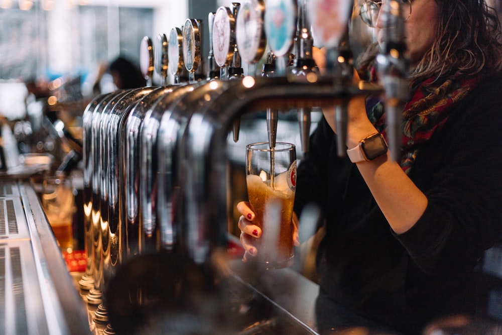 a woman pouring a glass of beer at a bar