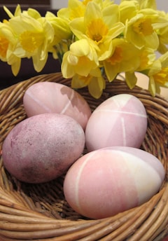 Colorful assortment of Easter eggs arranged in a decorative basket with flowers